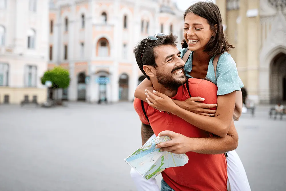 Happy young American expat couple embrace while sightseeing in European city