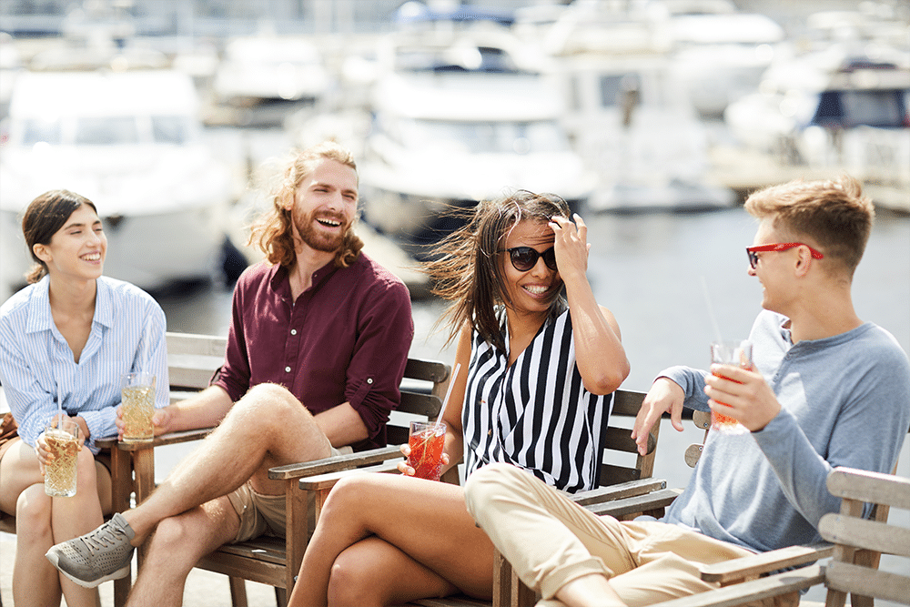 Four Americans abroad at boat marina, laughing and talking