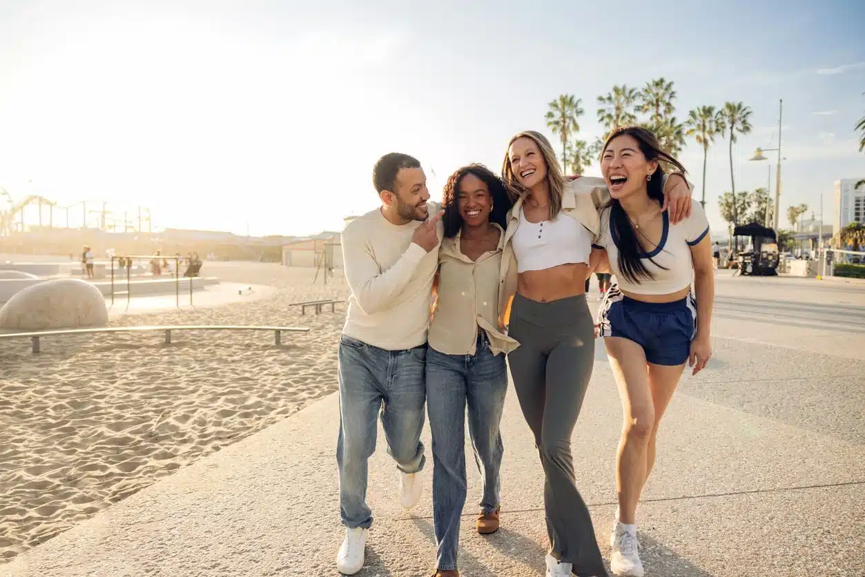 group of friends walking along a sunny california beach boardwalk with palm trees representing california state tax considerations for expats