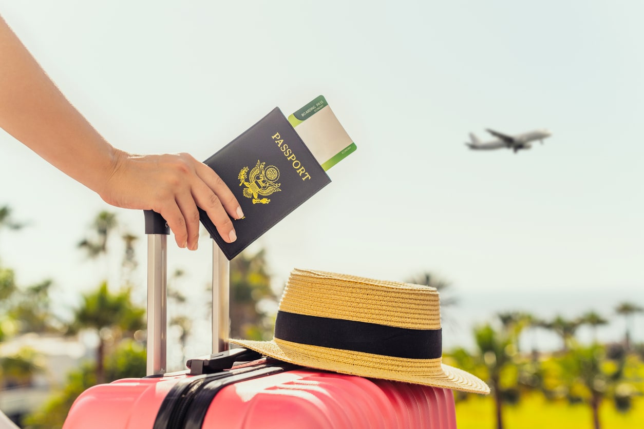 A U.S. passport resting on a suitcase with an airplane in the background, representing how Americans living abroad determine residency status for the Foreign Earned Income Exclusion tests.
