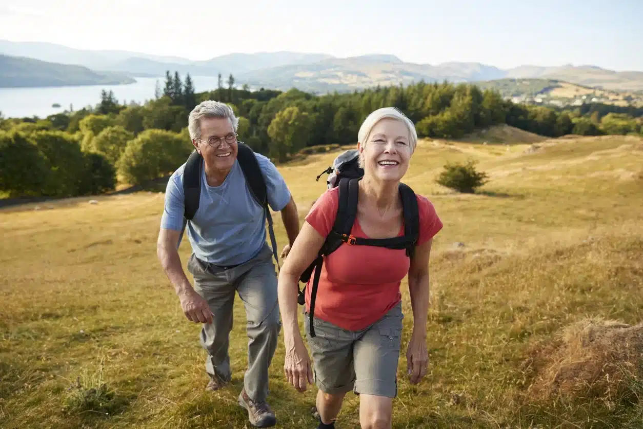 A retired couple hiking through a scenic countryside, representing Americans enjoying retirement abroad while planning for U.S. tax obligations on retirement income.