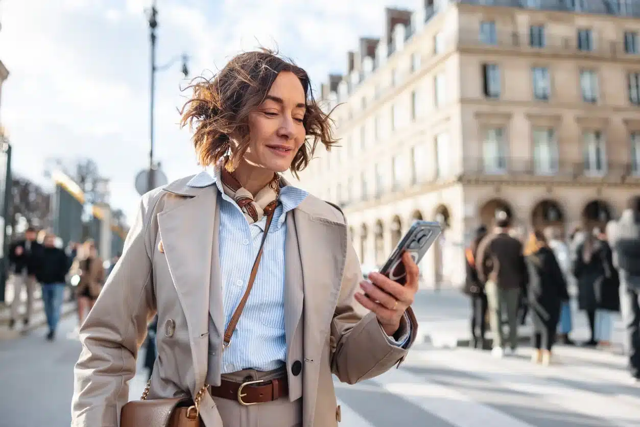 woman walking in paris city street using smartphone representing france inbound assignee