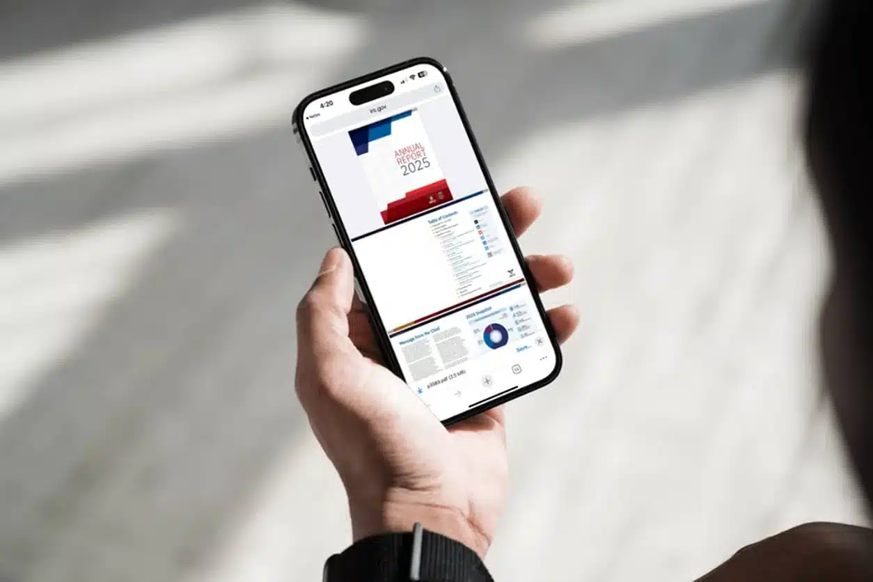 A person holding a smartphone displaying the IRS Criminal Investigation Annual Report.