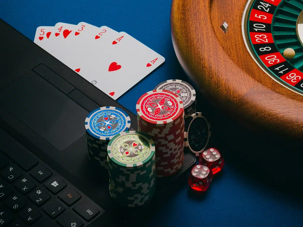 Casino chips, playing cards, dice, and a roulette wheel beside a laptop, representing gambling winnings and U.S. tax reporting rules for expats and foreign nationals.