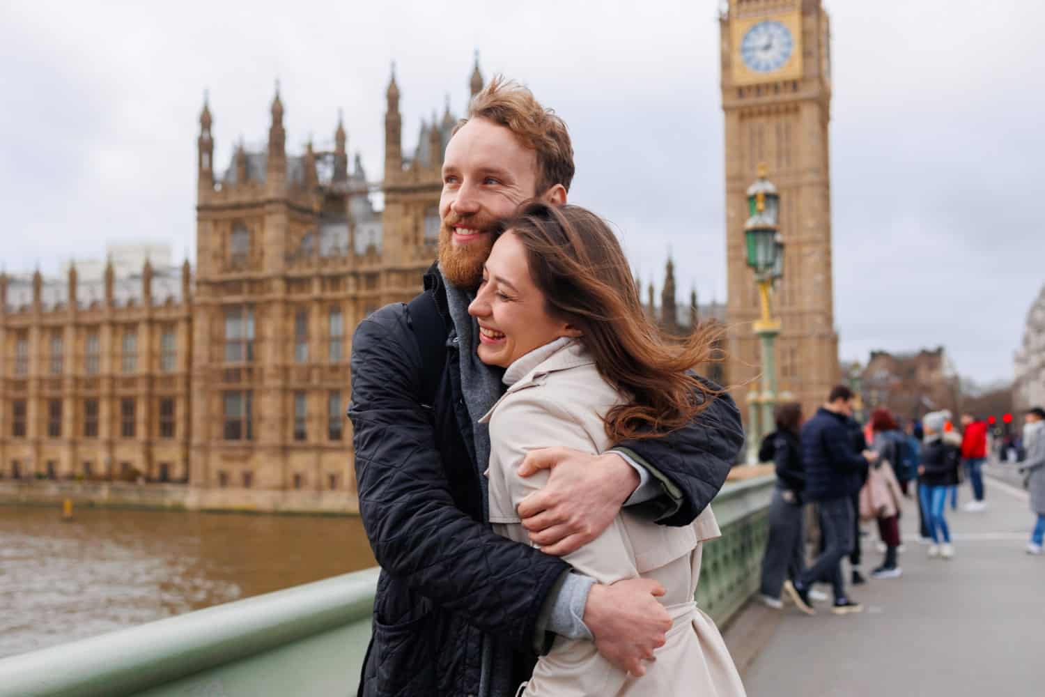 Couple embracing on Westminster Bridge in London with the Elizabeth Tower behind them.
